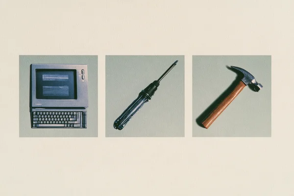 Vintage computer, screwdriver, and hammer on a textured background