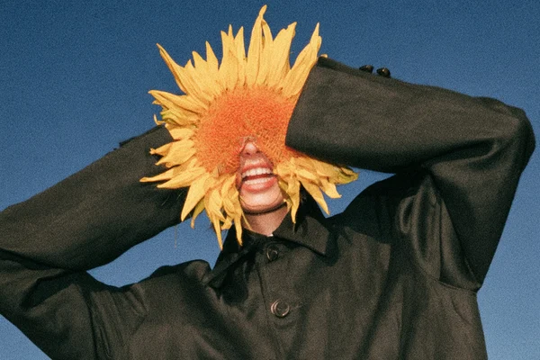 Person holding a sunflower over their face