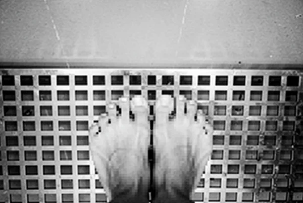 Bare Feet Standing on a Metal Grid Floor