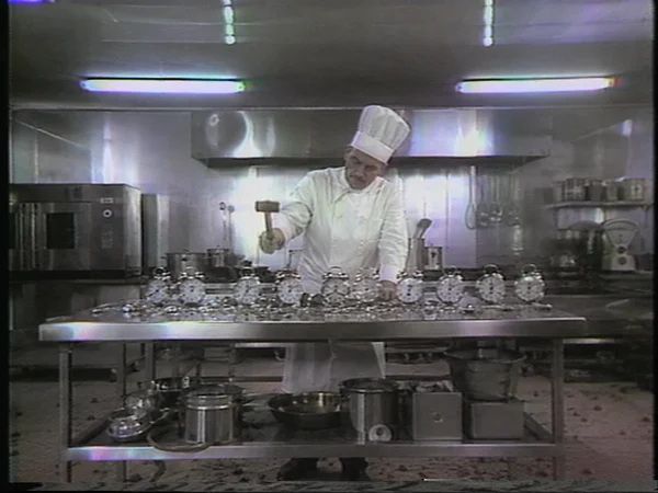 Chef Smashing Alarm Clocks in a Kitchen