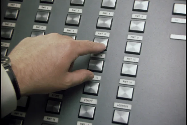 Hand pressing a button on a vintage control panel
