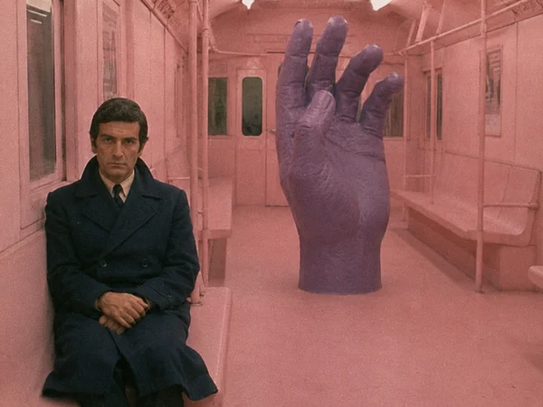 A Man Sitting Beside a Giant Purple Hand