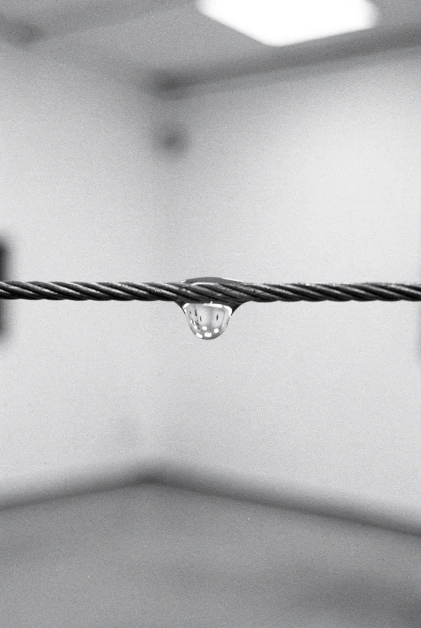 A Single Water Drop Hanging From A Metal Wire