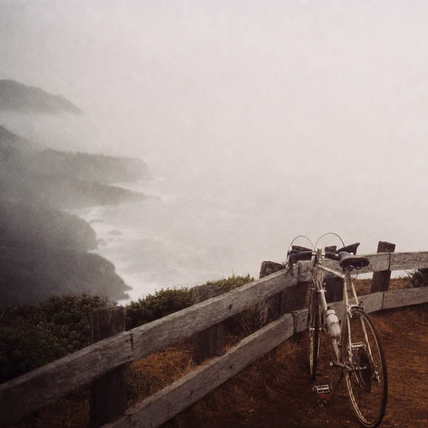 Bicycle parked by the misty ocean cliffside