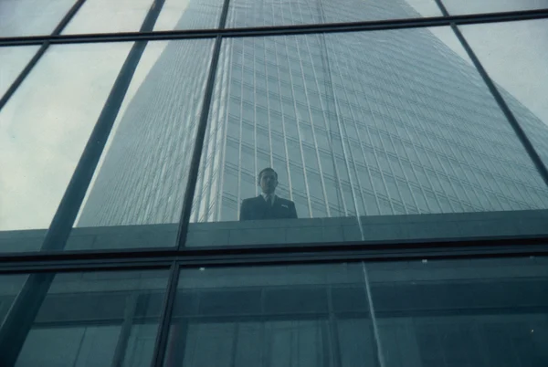 Man Standing Behind Glass Office Building