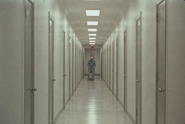 A Janitor Walking Down a Long Hospital Hallway