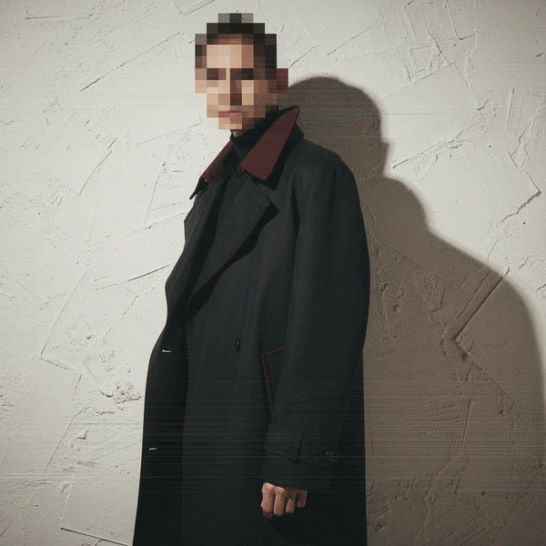 A Man in a Dark Overcoat Against a Textured Wall