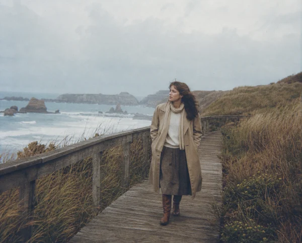A Woman Walking on a Coastal Boardwalk