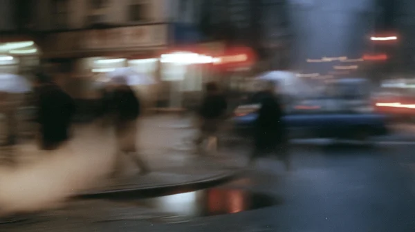 Blurred Figures Walking on a Rainy City Street