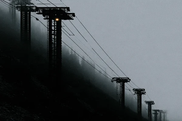 Ski Lift Towers Ascending a Foggy Mountain Slope
